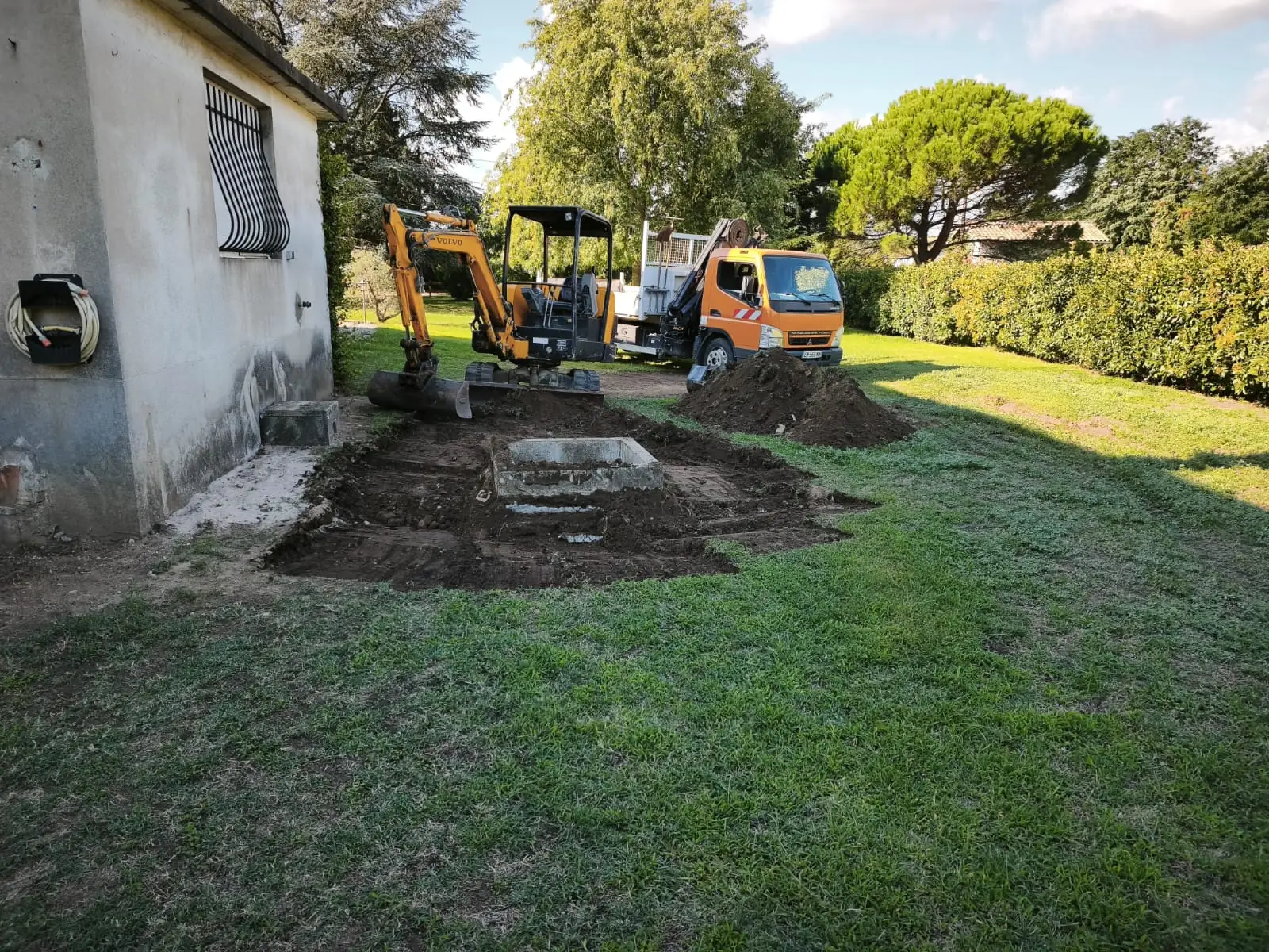 Mini-pelle et camion grue autour de la fouille, le long de la maison