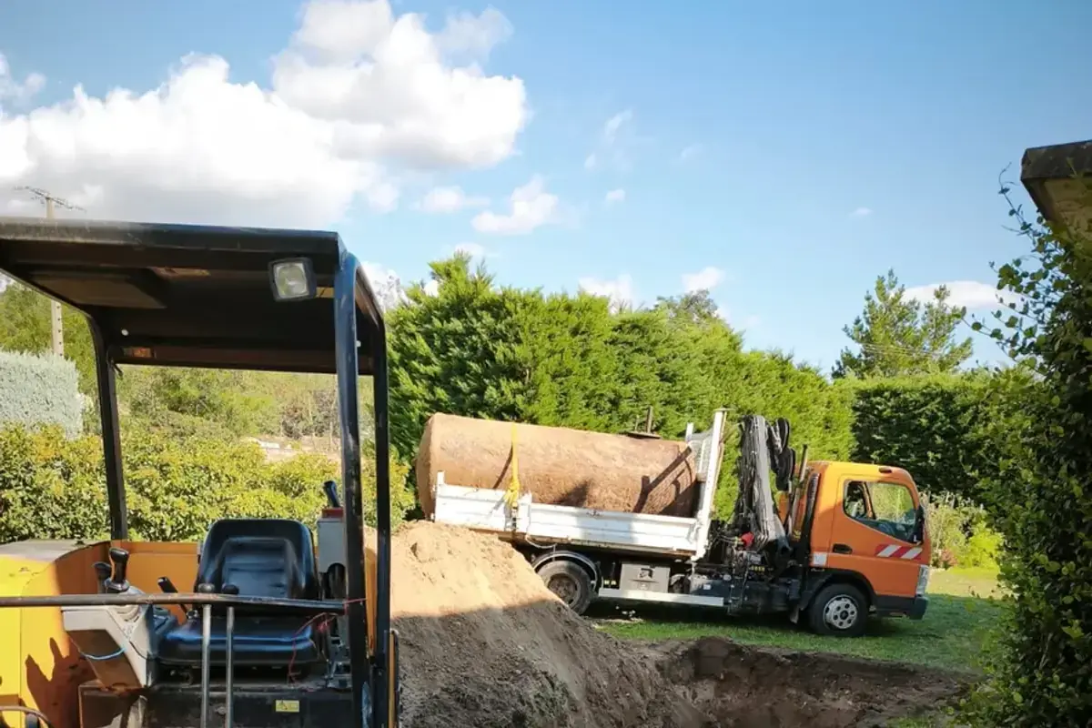 Camion benne de XAVSERVICE, grue repliée, chargé de la cuve déposée, mini-pelle au premier plan